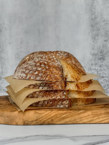 Sourdough bread slices stacked with parchment paper separating each slice.