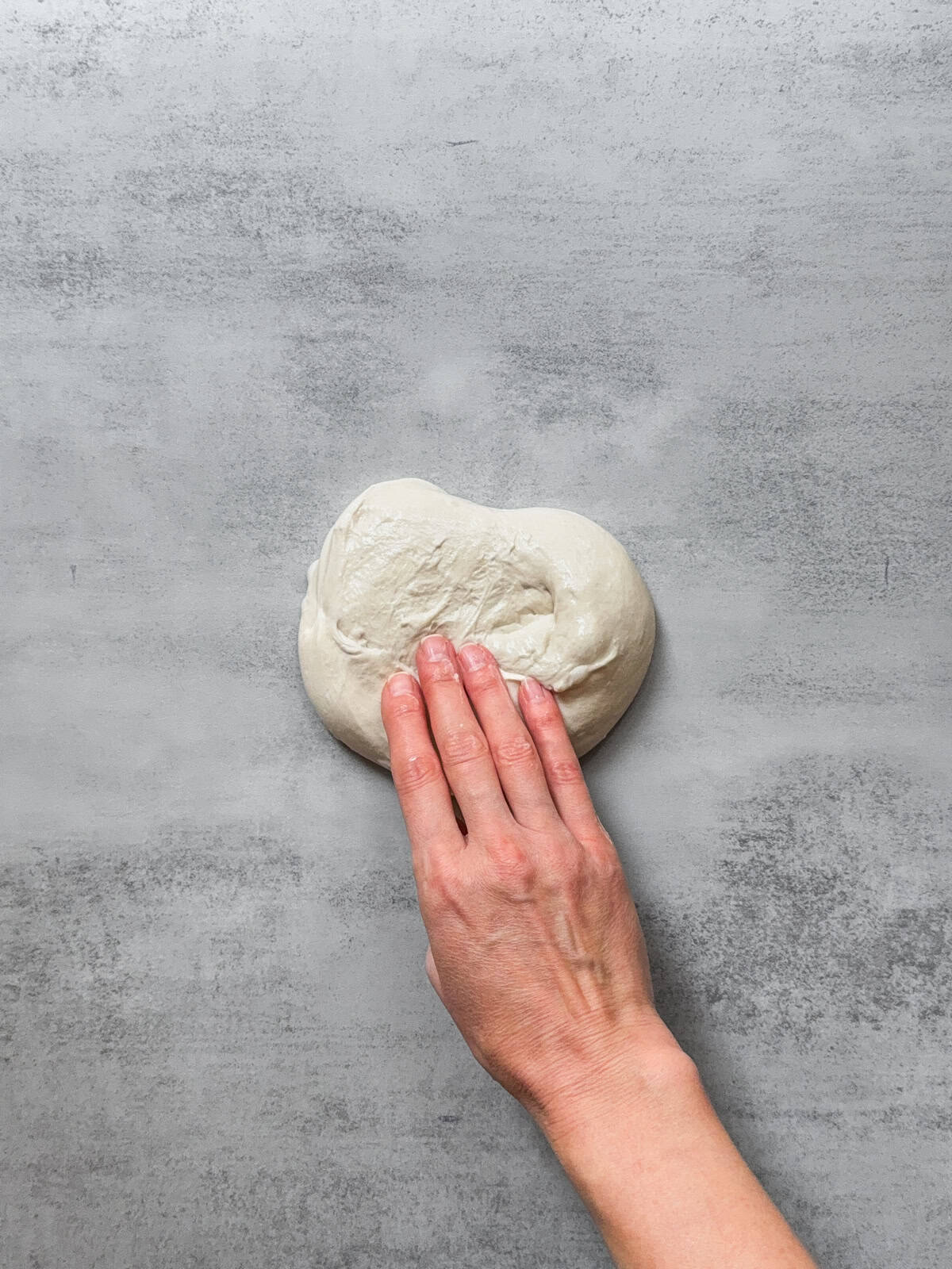 Hand holding the dough flipped upside down.