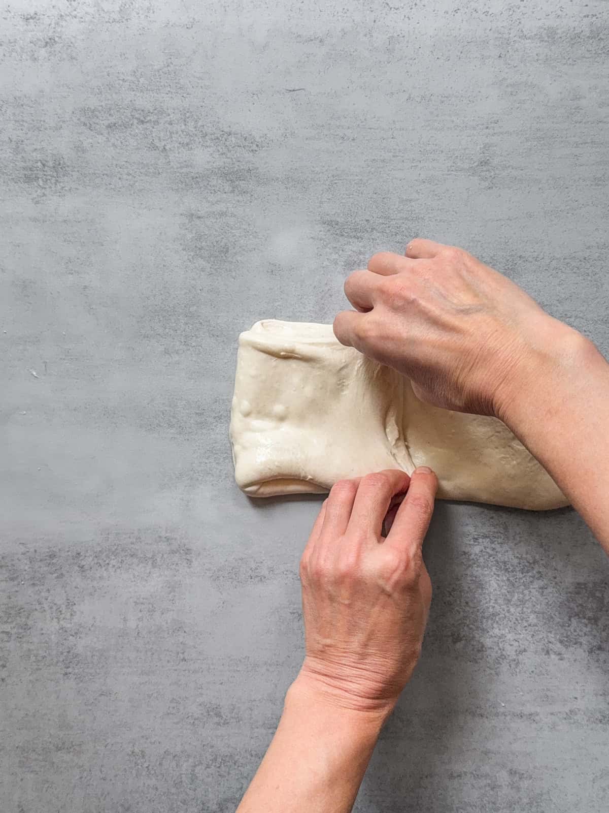 Hands folding the left third up over the layers.