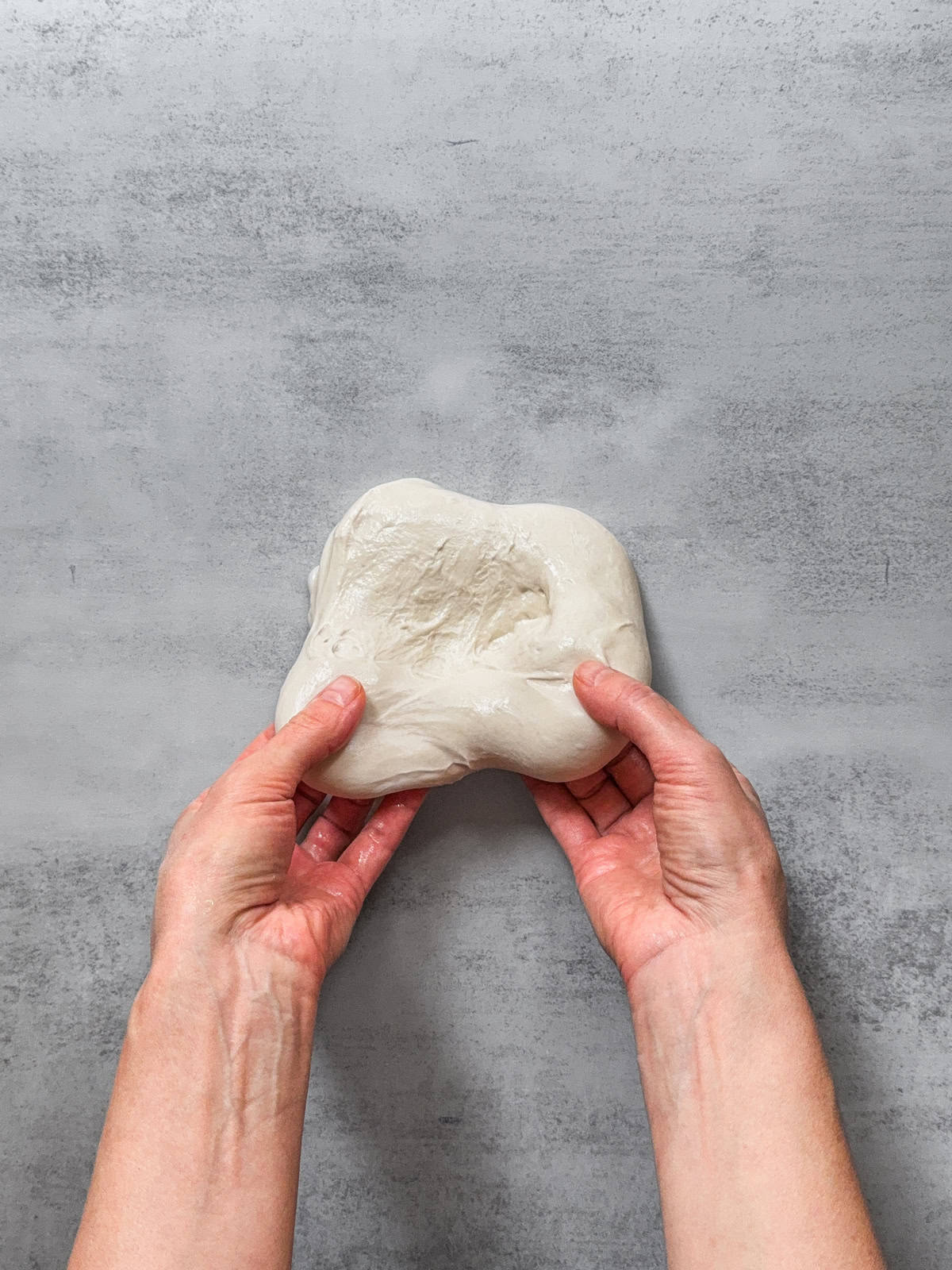 Hands pulling the dough away from the center.