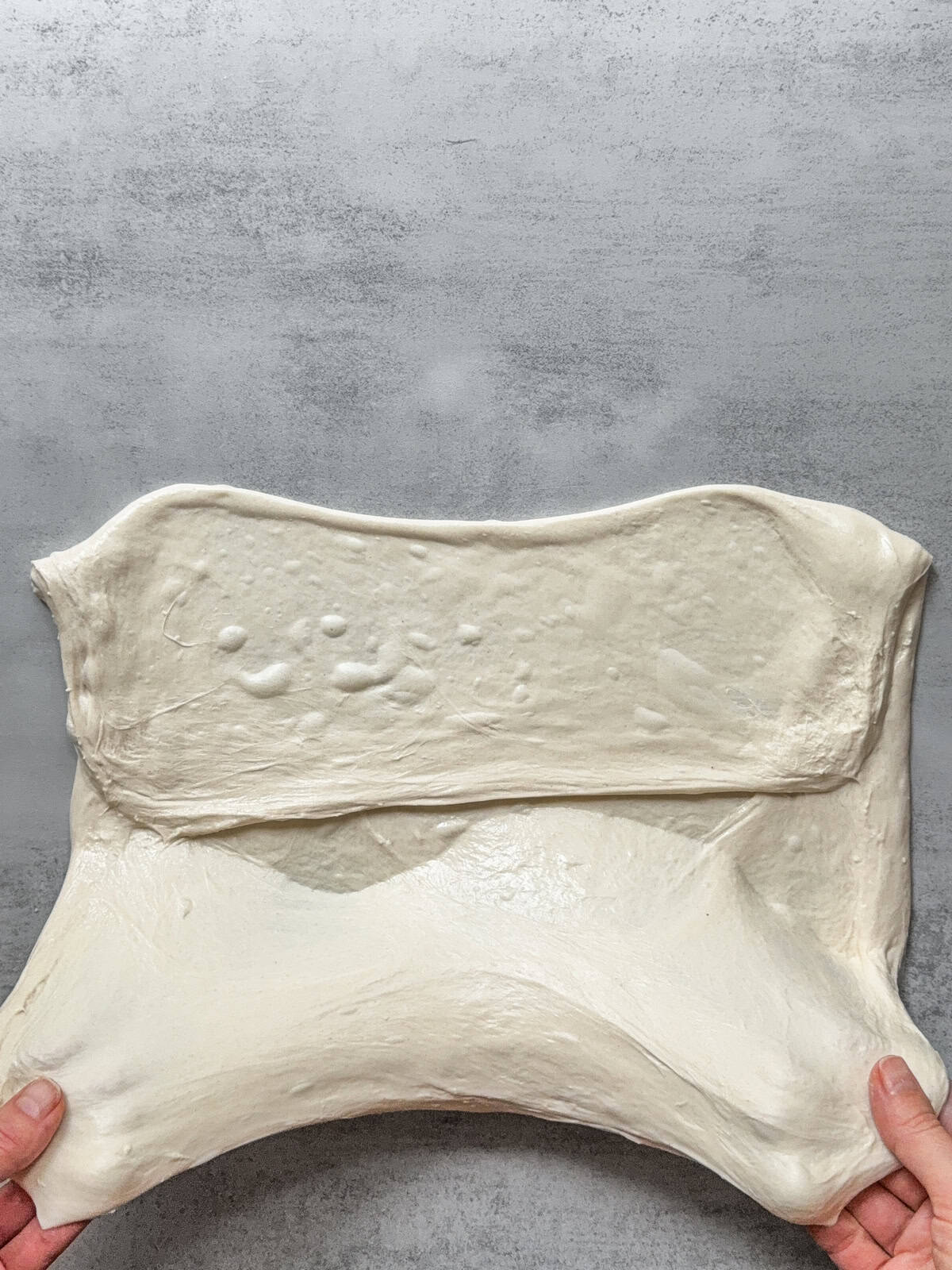 Hands holding the bottom third of the dough.