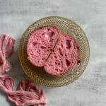 Halved pink sourdough bread in a wire-woven bowl.