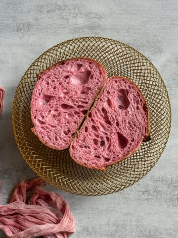 Halved pink sourdough bread in a wire-woven bowl.