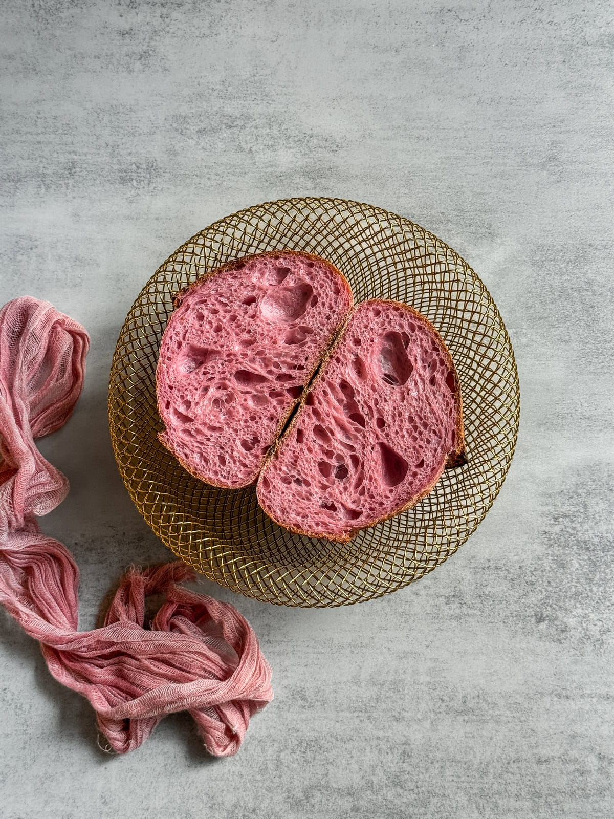 Halved pink sourdough bread in a wire-woven basket.