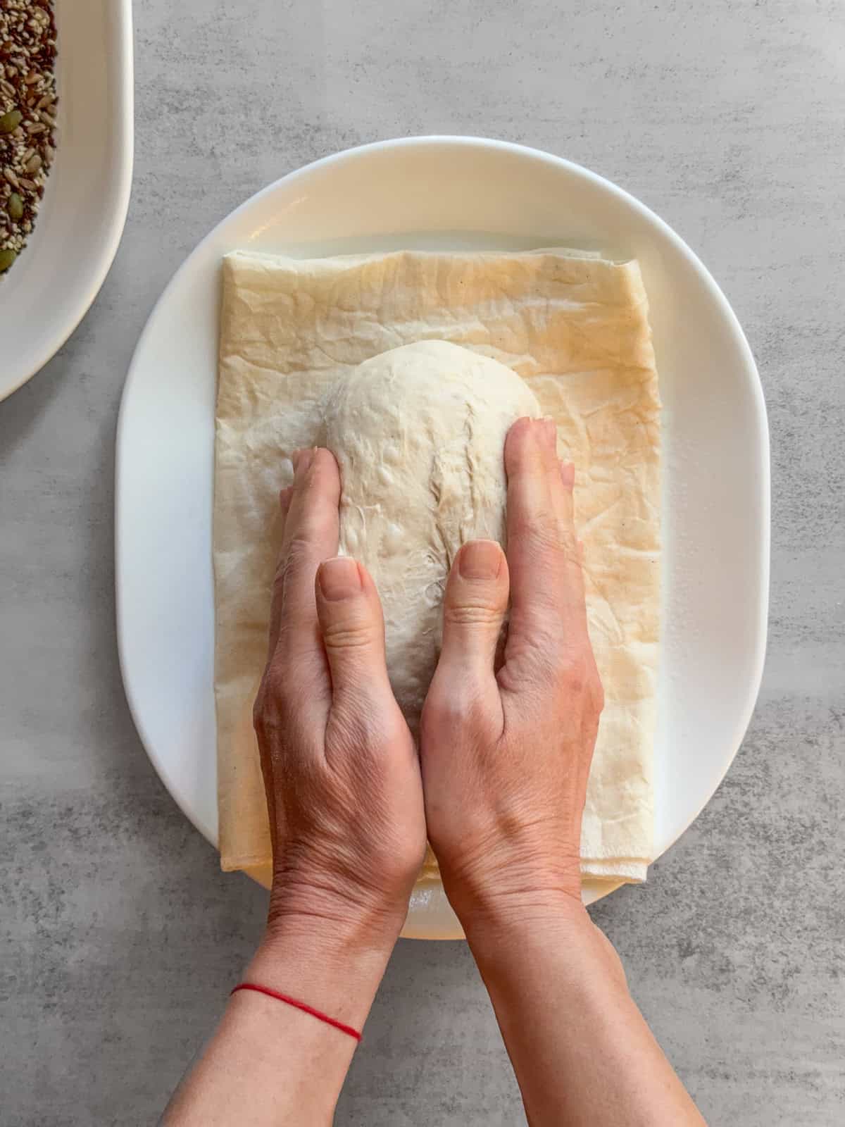 Hands holding the dough on a damp towel.