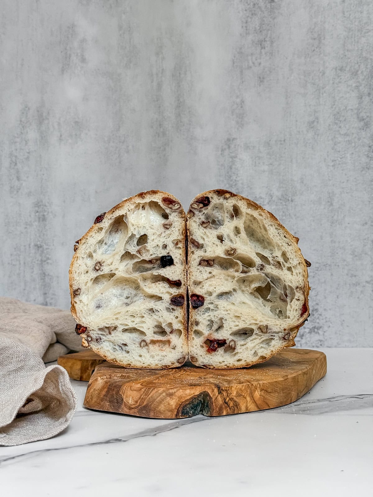 Freshly baked walnut cranberry sourdough bread, sliced to show interior texture.