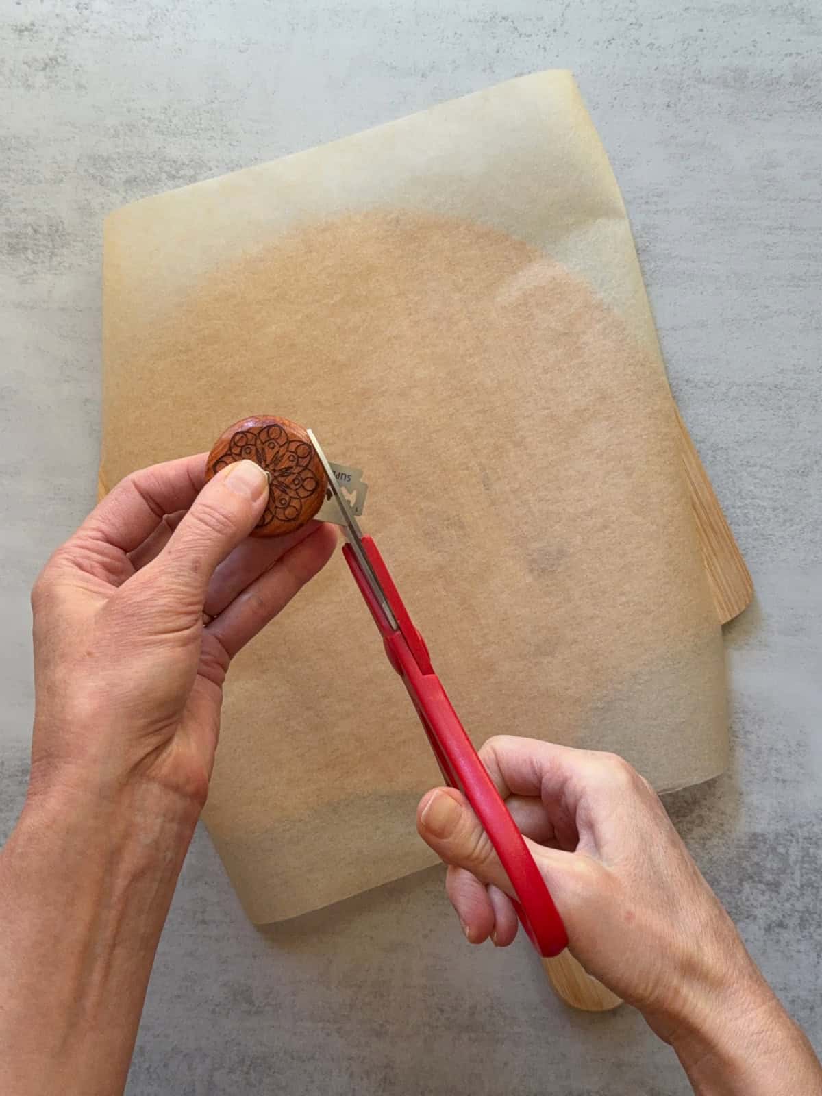 Hands cutting the UFO bread lame using scissors.