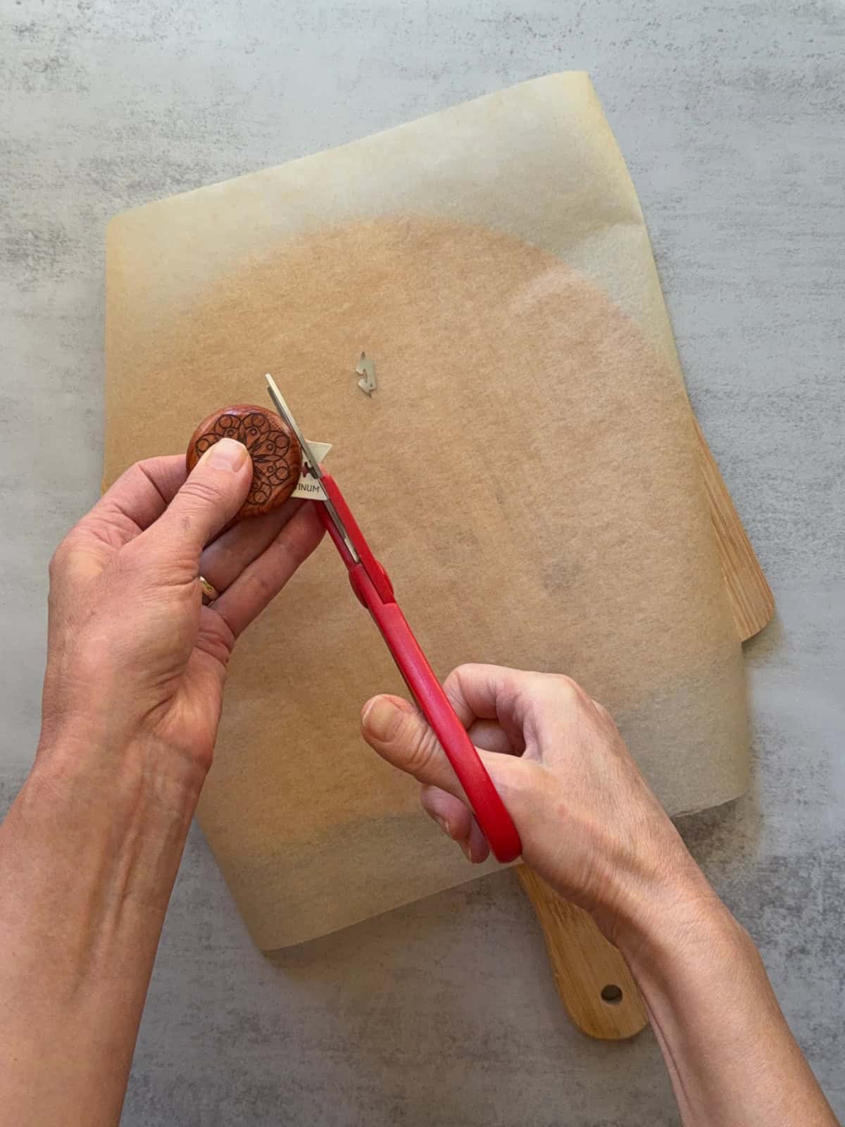Hands trimming the UFO bread lame with scissors.