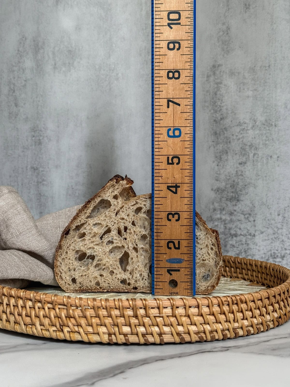 Half of a sourdough bread loaf with a wooden ruler measuring the oven spring.