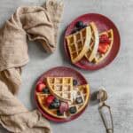 Sourdough waffles topped with fresh fruit and served on dessert plates.