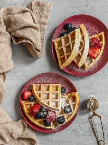Sourdough waffles topped with fresh fruit and served on dessert plates.