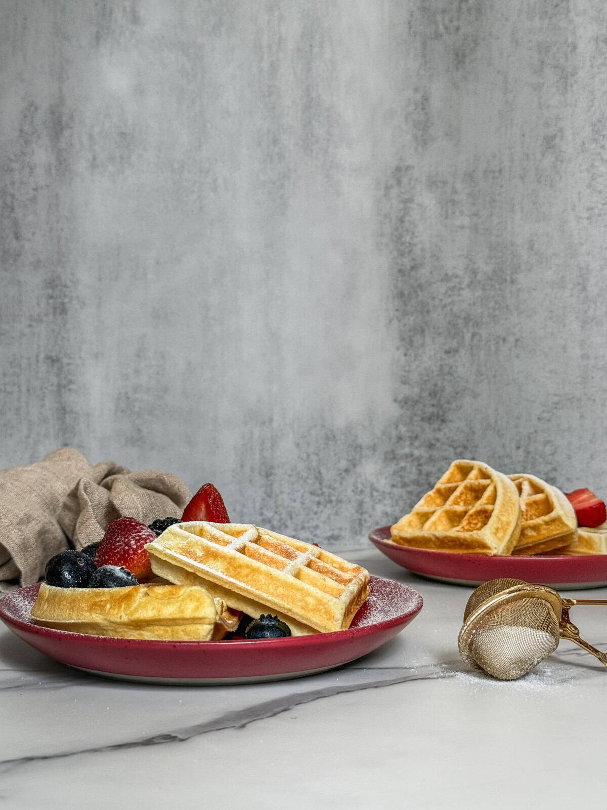 Sourdough discard waffles served with fresh frui and powdered sugar.